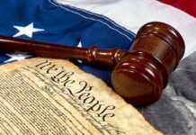 Gavel and Constitution on American flag background.