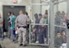 People detained behind fencing in a detention center.