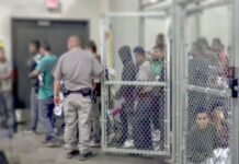 People detained behind fencing in a detention center.