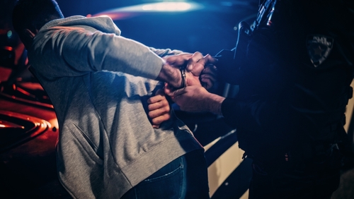 Person being handcuffed by police officer at night.