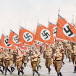 Nazi soldiers marching with swastika flags, World War II.