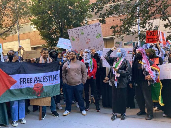 Protesters gather holding "Free Palestine" signs and banners.