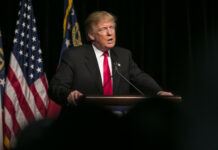 Donald Trump speaking at event with American flags.