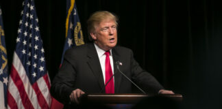 Donald Trump speaking at event with American flags.