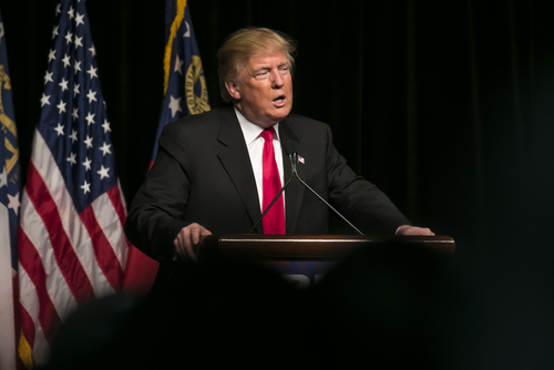 Donald Trump speaking at event with American flags.