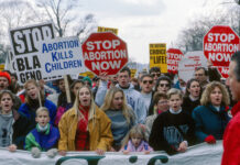 Protesters holding anti-abortion signs at a rally.