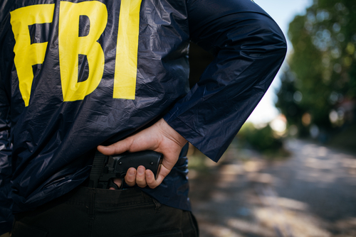 FBI agent holding a gun behind the back.