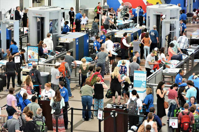 Crowd at an airport security checkpoint with TSA officers.