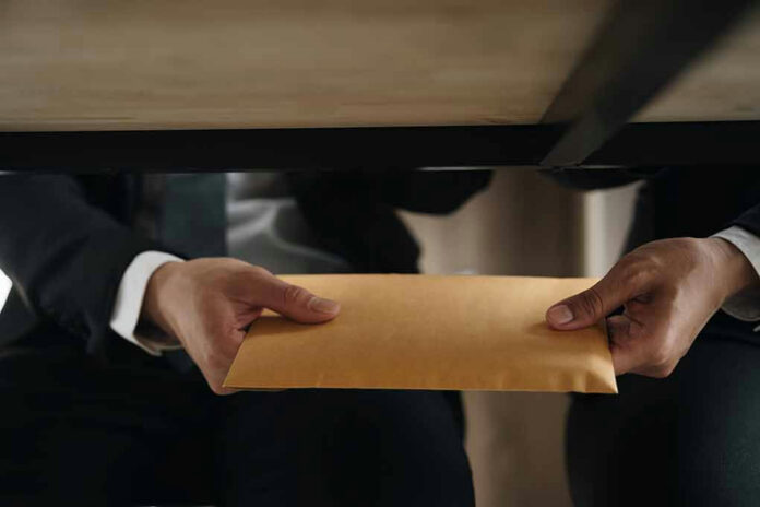 Two people exchanging an envelope under a table.