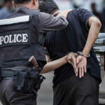 Police officer arresting a person in handcuffs.