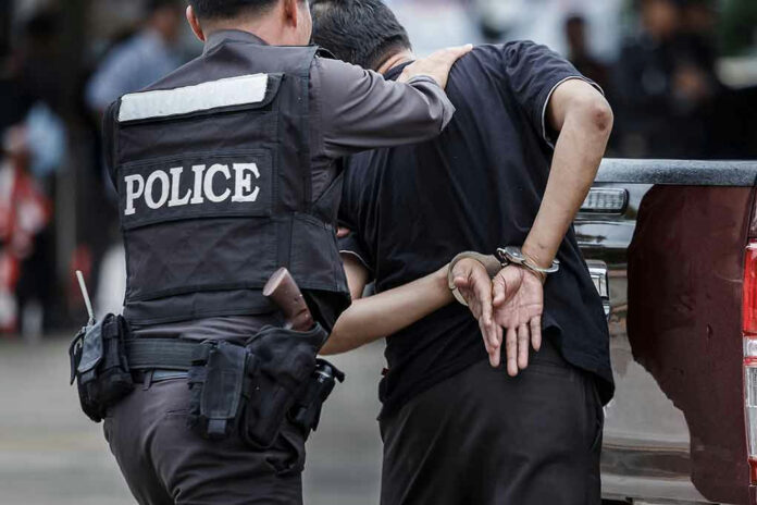 693957643 Police officer arresting a person in handcuffs.