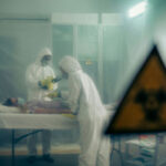 Americans STRANDED – High Court FREEZES U.S. Ebola Plan… Two scientists examining a patient with biohazard sign visible.