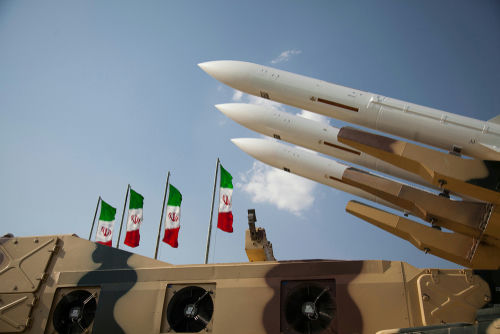 Military missiles displayed with Iranian flags in the background