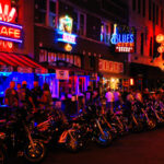 Vibrant street scene at night with neon signs and parked motorcycles