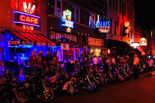 Vibrant street scene at night with neon signs and parked motorcycles