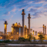UAE Threatens MILITARY Response After ATTACK Industrial plant with smokestacks at dusk.