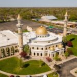 San Diego Mosque UNDER Siege: SHOCKING Details Aerial view of a mosque with golden domes and minarets surrounded by greenery