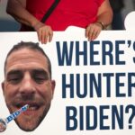 Hunter’s Scripture SHOCKER—Candace Owens Squirming? A protestor holding a sign with a large image of a mans face and the text WHERES HUNTER BIDEN?