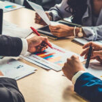 RECESSION? Ottawa Spins, Wallets Scream People discussing charts and graphs at a meeting.
