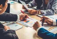 RECESSION? Ottawa Spins, Wallets Scream People discussing charts and graphs at a meeting.