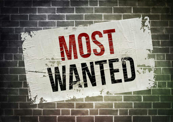 Most Wanted poster on brick wall.