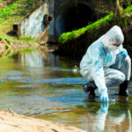 MAJOR WARNING — Iranian Hackers INFILTRATE U.S. Water Person in protective gear collecting water sample from stream.