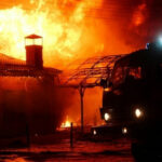 Fires ENGULF Ancient Town — Why is This Kept QUIET? Building on fire with a firetruck in foreground.