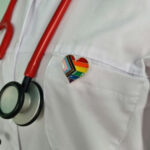 YOUTH GENDER CARE Advocate NOW TOP of SOCIETY for Pediatrics?? Doctors coat with stethoscope and rainbow heart badge.