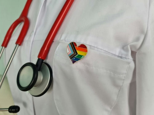 shutterstock_2269982403 Doctors coat with stethoscope and rainbow heart badge.