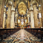Interior of a grand cathedral with empty pews.