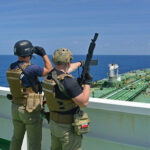 Gripping Raid, Missing Proof—Who Authorized This? Armed security team on a ship deck overlooking a large tanker at sea