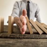 Judge STOPS Paxton — But BOMBSHELLS Linger Hand stopping falling wooden dominoes on a table