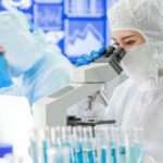 Scientists examining samples under microscopes in a laboratory.