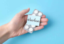 Doctor Study vs. Bleeding Trial: Who’s Right? Hand holding pills labeled abortion on blue background.