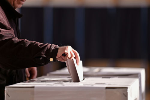 Person placing a ballot into a voting box