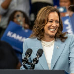 Smiling woman speaking at a crowded event indoors