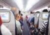 Airplane cabin aisle with passengers seated and seatback screens