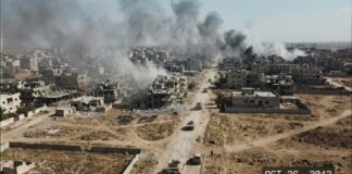 Aerial view of a war-torn city with smoke rising from buildings